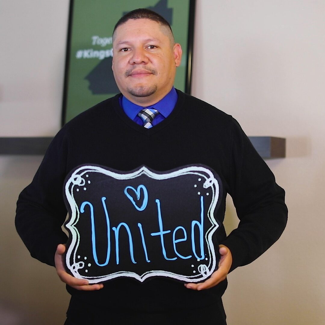 Employee holding a sign that says United
