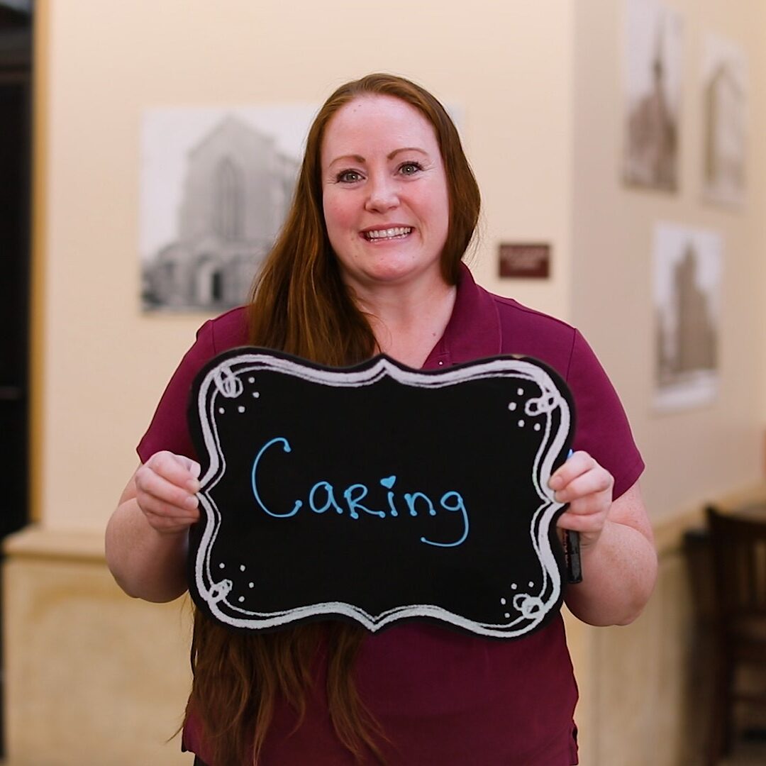 Employee holding a sign that says Caring